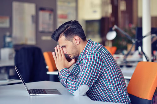 Man appearing stressed at laptop.