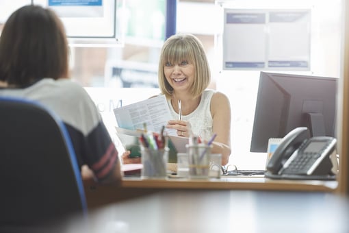 woman holding a piece of paper talking to someone